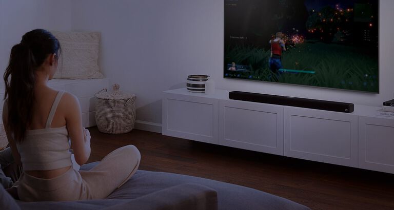 a couple watching TV with a large sound bar sitting under it. a couple watching TV with a large sound bar sitting under it.