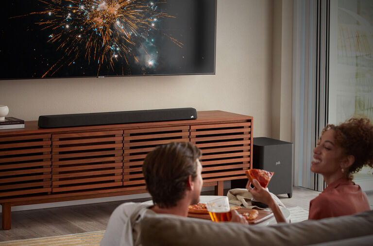 A couple eating pizza and watching TV. A couple eating pizza and watching TV.