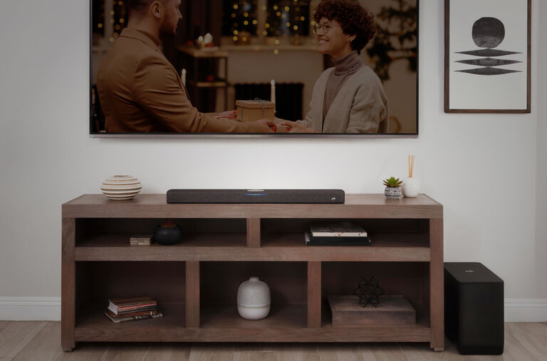 A mounted TV with a soundbar on the table below, and a subwoofer on the floor beside the table. A mounted TV with a soundbar on the table below, and a subwoofer on the floor beside the table.